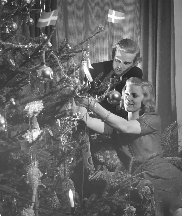 Framed Print : Christmas in the 1940s. A young couple is putting christmas decorations on the christmas tree Framed Print : Christmas in the 1940s. A young couple is putting christmas decorations on the christmas tree