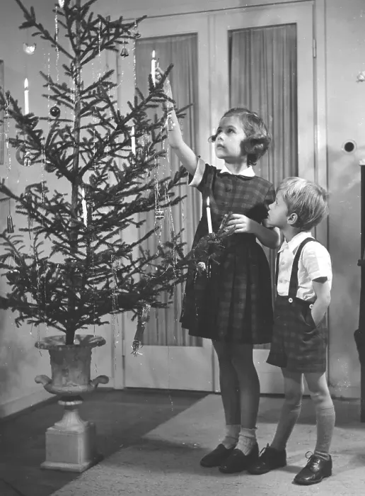 Framed Print : Christmas in the 1950s. A girl and a boy is lighting the candles in the christmas tree. They are nicely dressed for christmas. Sweden 1952