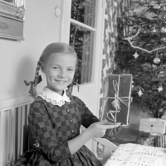 Framed Print : Christmas in the 1960s. A young girl holds a nice wrapped christmas package. Sweden 1963 Ref 4827