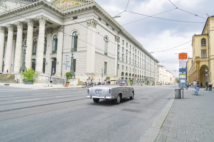 Framed Print : A classic car drives alongside a magnificent building in Munich