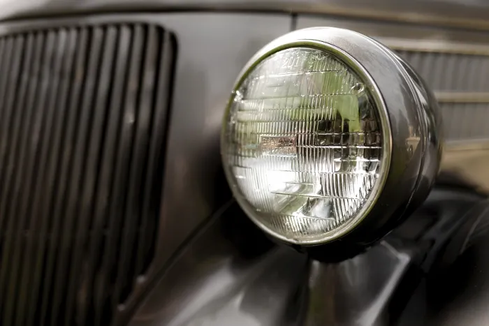 Framed Print : Detail of a classic car's headlight with chrome finish on a dark body in St