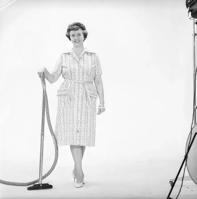 Framed Print : Cleaning day in the 1960s. A woman is standing holding a vacuum cleaner Framed Print : Cleaning day in the 1960s. A woman is standing holding a vacuum cleaner