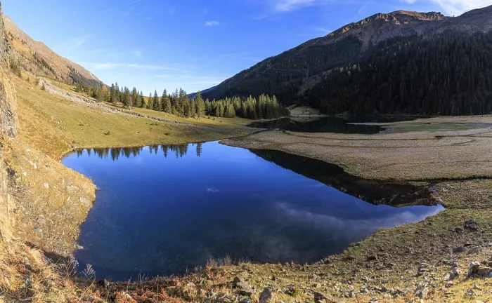 Framed Print : A clear lake surrounded by mountains and forests