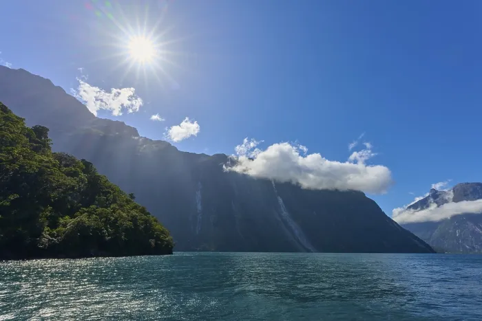 Framed Print : Clear sun over a fjord, surrounded by majestic mountains and a slightly cloudy sky