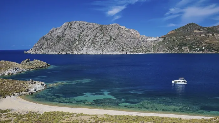 Framed Print : Clear turquoise water with a boat and mountains in the background under a blue sky