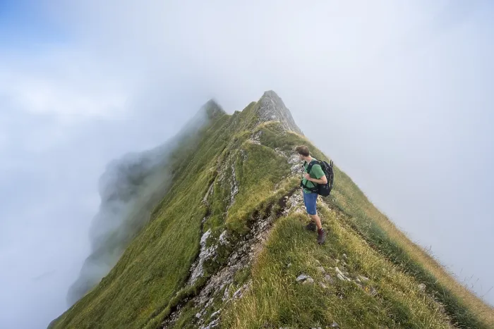 Framed Print : Climbers on a narrow ridge, steep grassy mountains in the fog