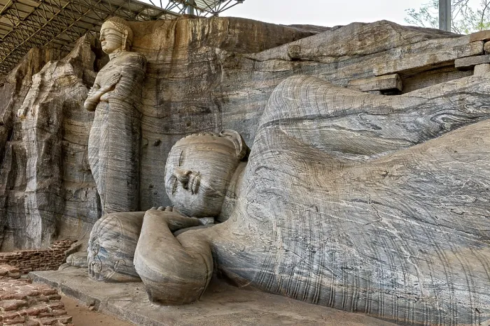 Framed Print : Close-up of the artistic detail of a large reclining Buddha statue next to a standing figure carved out of rocks