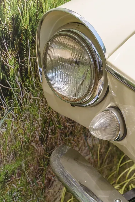 Framed Print : Close-up of a cream-coloured vintage car headlight against a green background