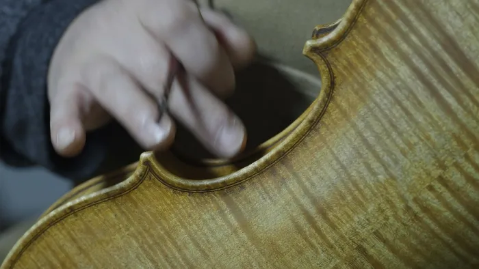 Framed Print : Close-up of a hand working on the intricate details of a violin