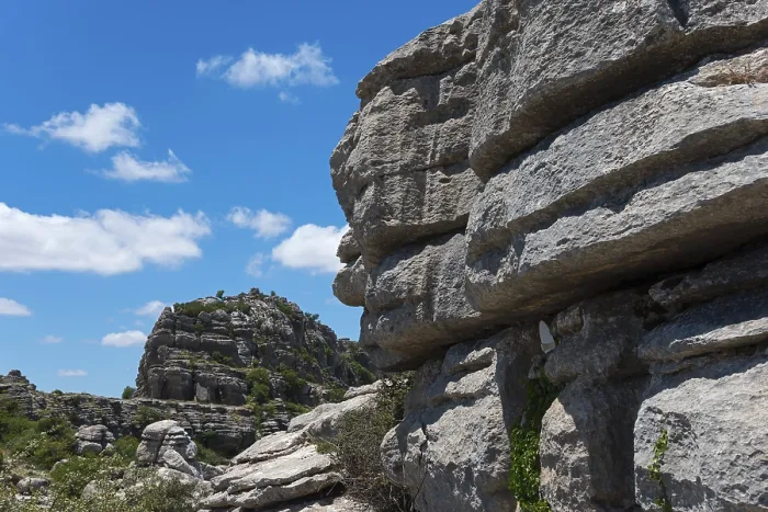 Framed Print : Close-up of large rocks with blue sky and clouds in the background and green vegetation