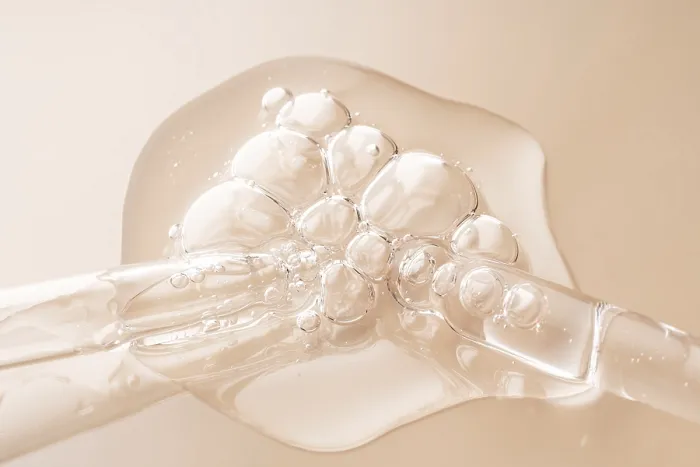 Framed Print : Close-up of transparent serum drops on a beige surface