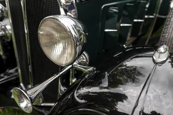 Framed Print : Close-up of a vintage green car's chrome horn and headlight with reflective elements in St