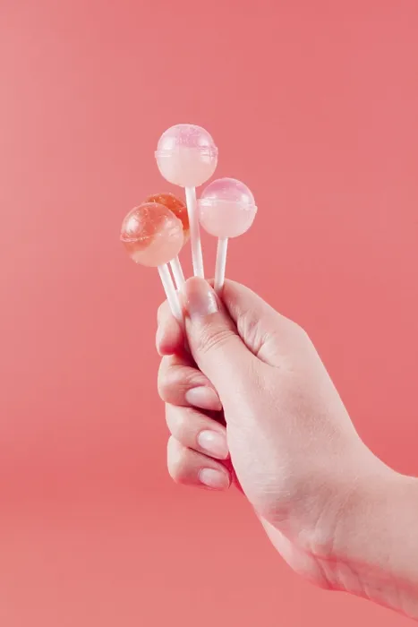 Framed Print : Close up womans hand holding lollipops against coral backdrop