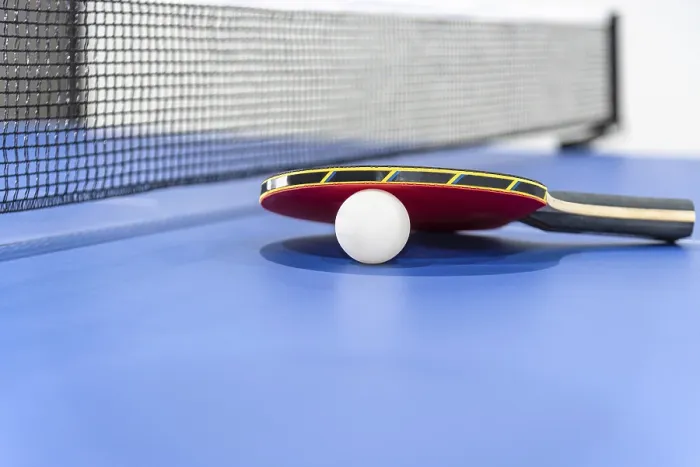 Framed Print : Closeup red table tennis racket and a white ball on the blue ping pong table with a black net