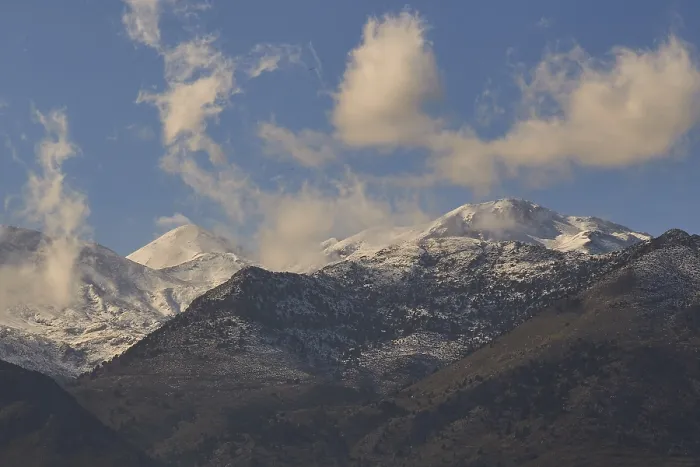 Framed Print : Cloudy mountain landscape with snow-capped peaks under a clear sky