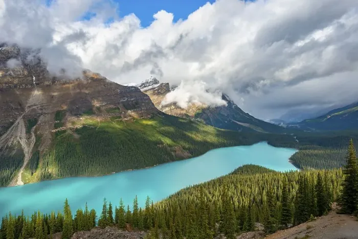 Framed Print : Cloudy mountain peaks, turquoise glacial lake surrounded by forest