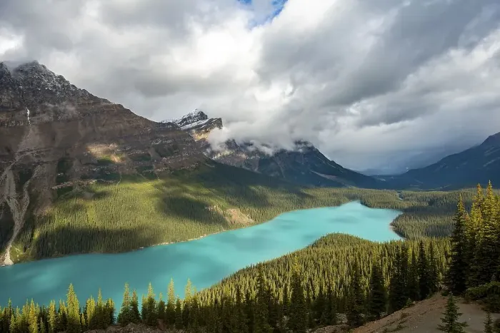Framed Print : Cloudy mountain peaks, turquoise glacial lake surrounded by forest Framed Print : Cloudy mountain peaks, turquoise glacial lake surrounded by forest