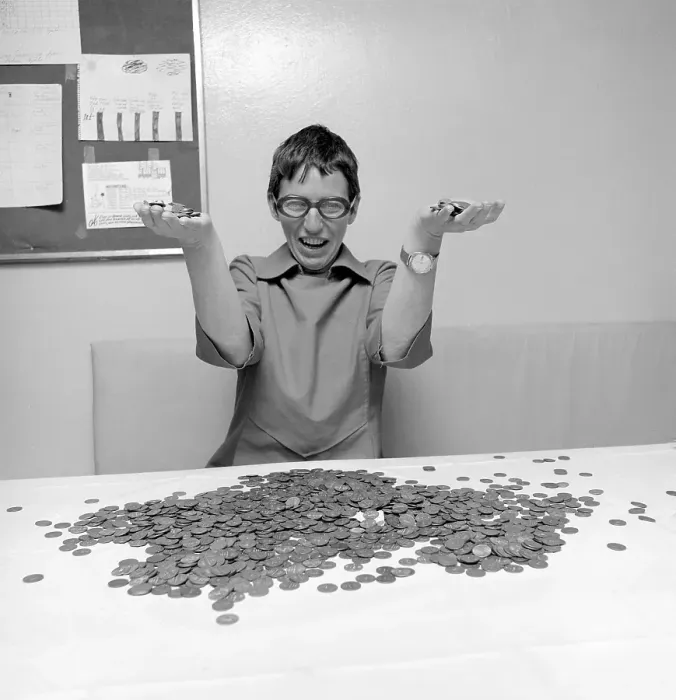 Framed Print : Coins. A woman with a large amount of coins in front of her, looking really happy. 1971. Conard ref 6019