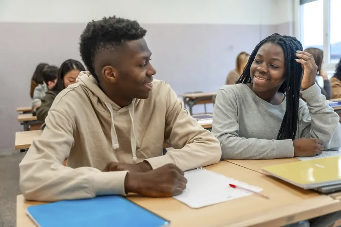 Framed Print : Two college students smiling and engaging in conversation during a lesson Framed Print : Two college students smiling and engaging in conversation during a lesson