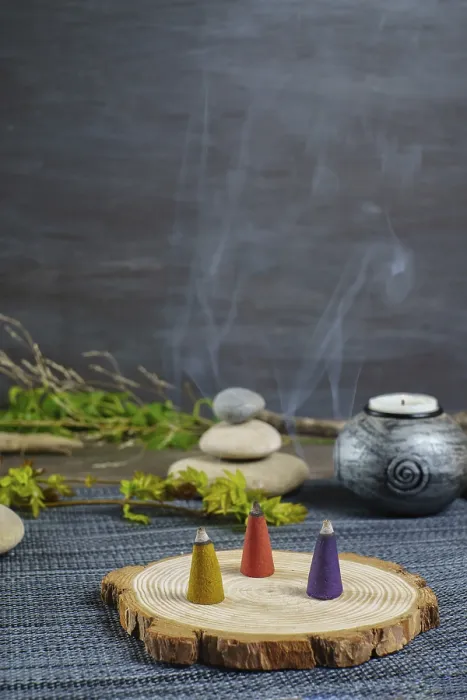 Framed Print : Colorful incense cones on a wooden disk with candles and zen stones stacked on top of them