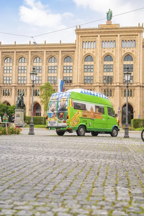 Framed Print : A colourfully painted bus in front of a historic building with a cobbled street and lanterns