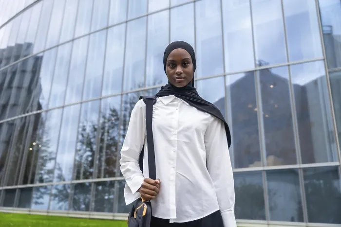 Framed Print : Confident young black woman wearing a hijab and carrying a shoulder bag