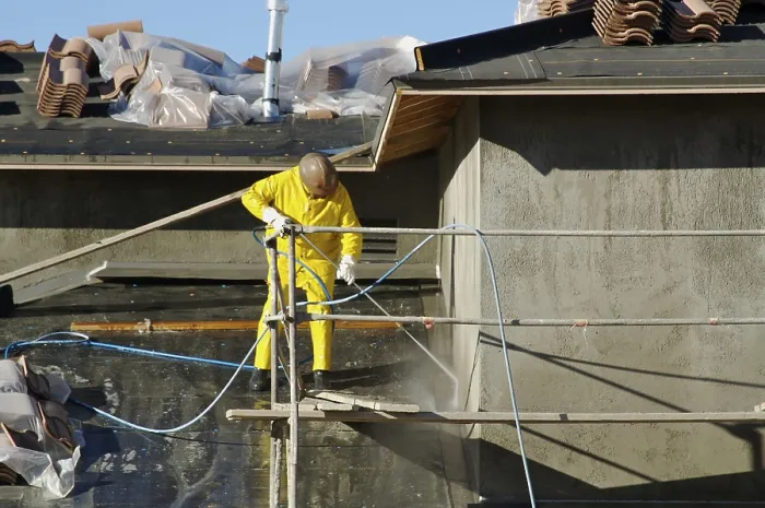 Framed Print : Construction worker pressure washes fresh applied surface of new home exterior