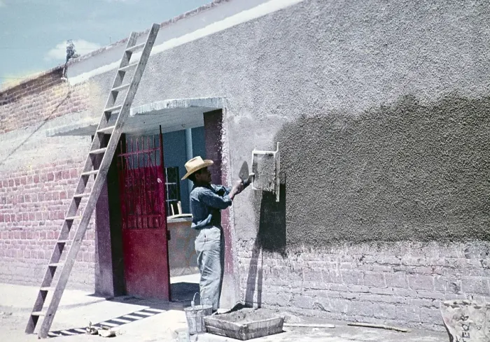 Framed Print : Construction worker throwing cement through a sieve to make wall panelling over modern red bricks, Mexico around 1961