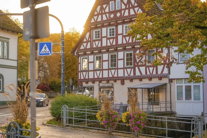 Framed Print : Cosy half-timbered house in autumn light with street sign and flowers Framed Print : Cosy half-timbered house in autumn light with street sign and flowers