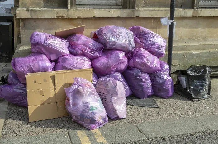 Framed Print : Council bags of rubbish waste piled on street corner