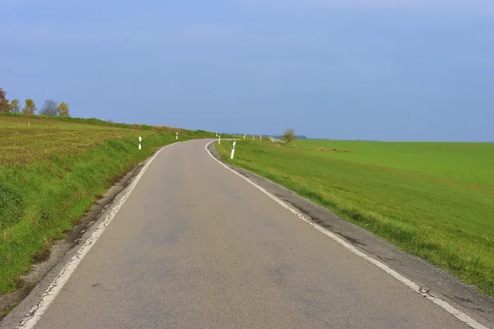 Framed Print : Country road leads through wide green fields under a clear sky Framed Print : Country road leads through wide green fields under a clear sky