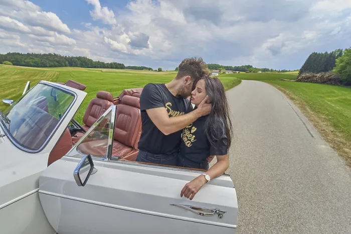 Framed Print : Couple sharing an affectionate moment by a white convertible on a rural road Framed Print : Couple sharing an affectionate moment by a white convertible on a rural road