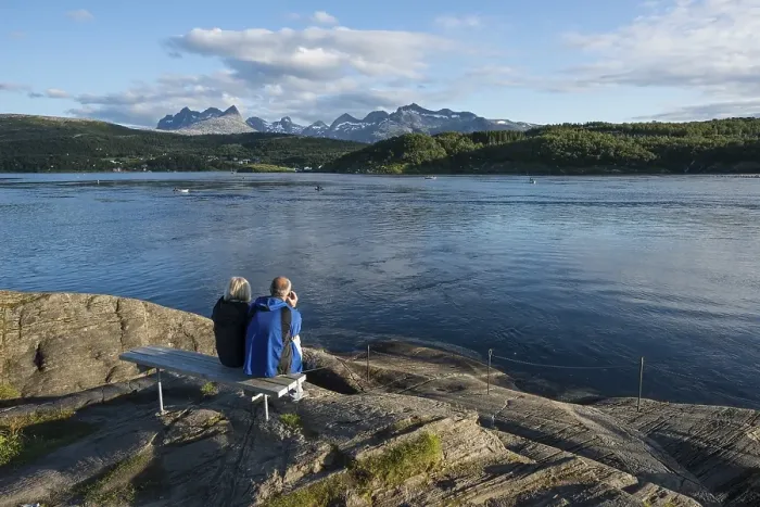 Framed Print : Couple sitting on a bench looking out to the tidal Saltstraumen strait in the evening light