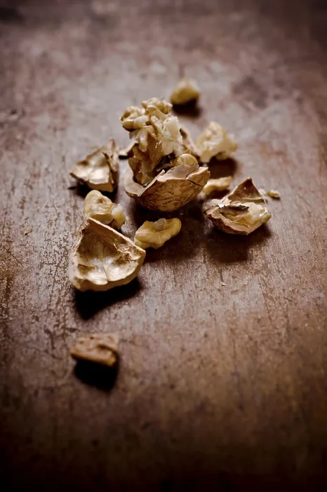 Framed Print : Cracked walnut shells and pieces scattered on a rustic wooden surface
