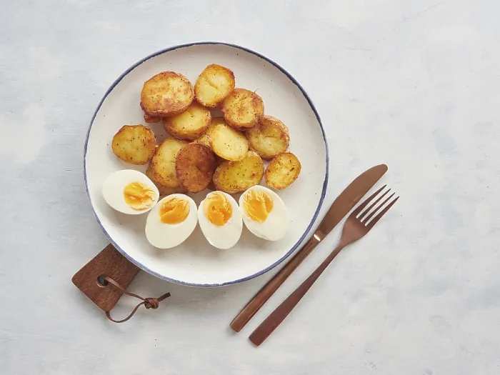 Framed Print : Crispy golden brown roasted potatoes sliced and hard boiled egg halves plate