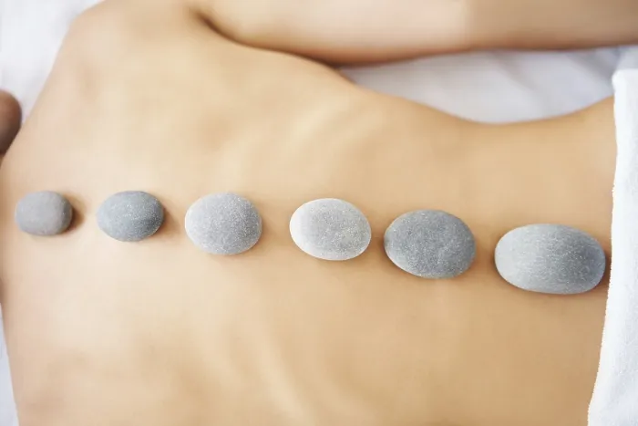 Framed Print : Cropped close up female relaxing in spa salon with hot stones on her back