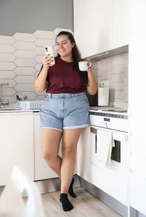 Framed Print : A curvy woman in casual clothes stands in a bright kitchen