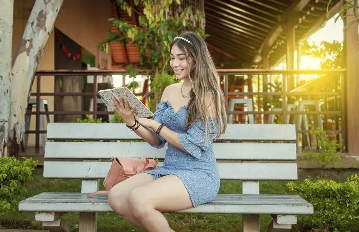 Framed Print : A cute girl sitting on a bench reading a book