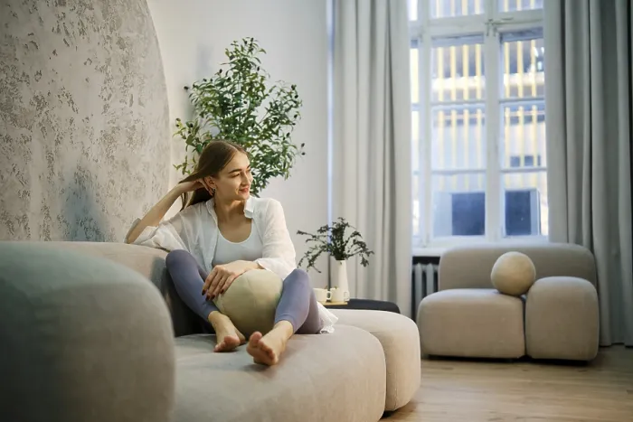 Framed Print : A cute woman is sitting on a light sofa in a modern room Framed Print : A cute woman is sitting on a light sofa in a modern room