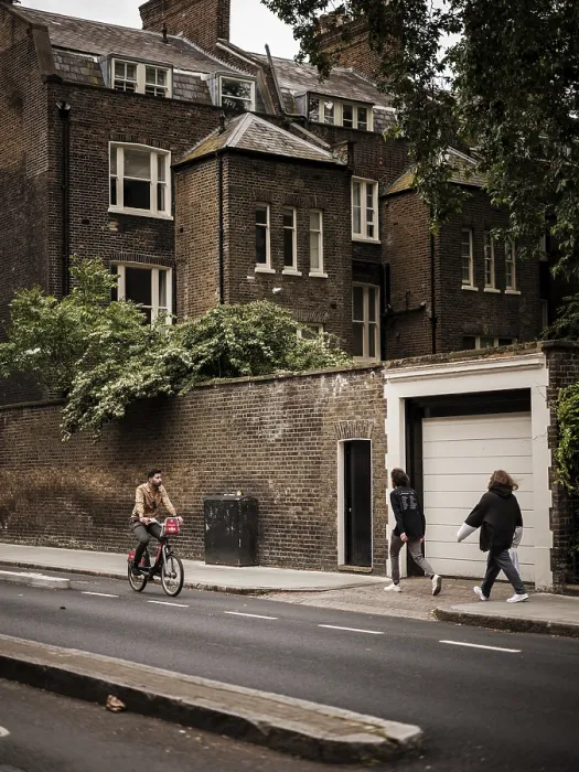 Framed Print : Cyclist and pedestrians pass a historic brick building on a cloudy day in Greater London