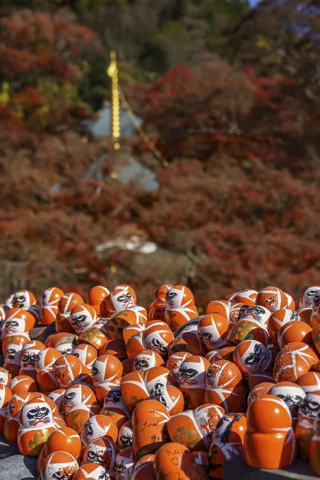 Framed Print : Many Daruma figures in front of an autumn mountain panorama creating a spiritual atmosphere