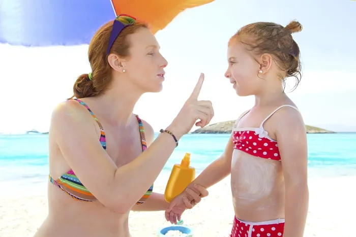 Framed Print : Daughter and mother in beach with sunscreen in bikini