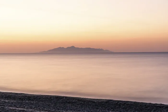 Framed Print : Dawn at sunrise, view from the lava beach near Kamari to the island of Anafi