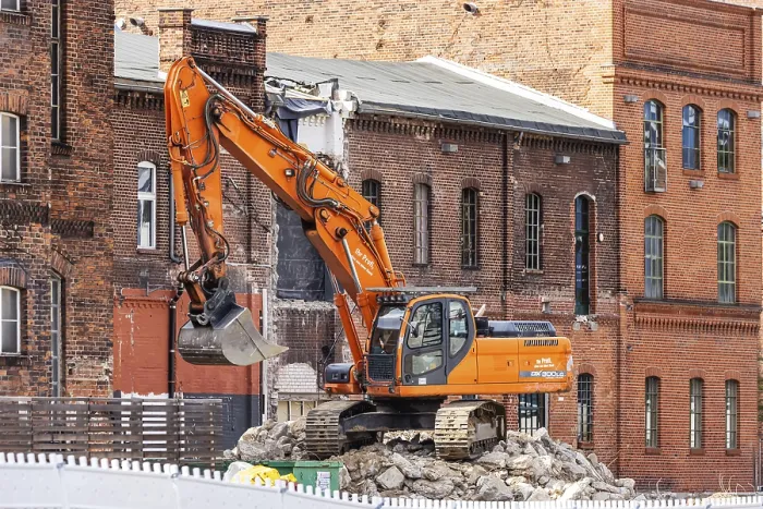 Framed Print : Demolition excavator in front of historic brick buildings