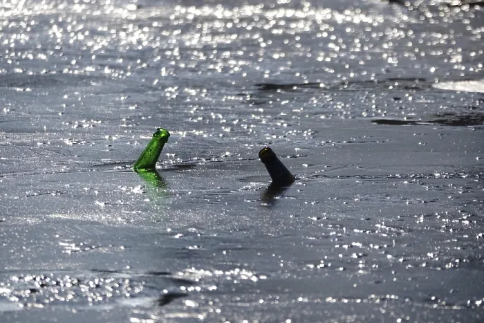 Framed Print : Discarded glass bottles in a frozen lake