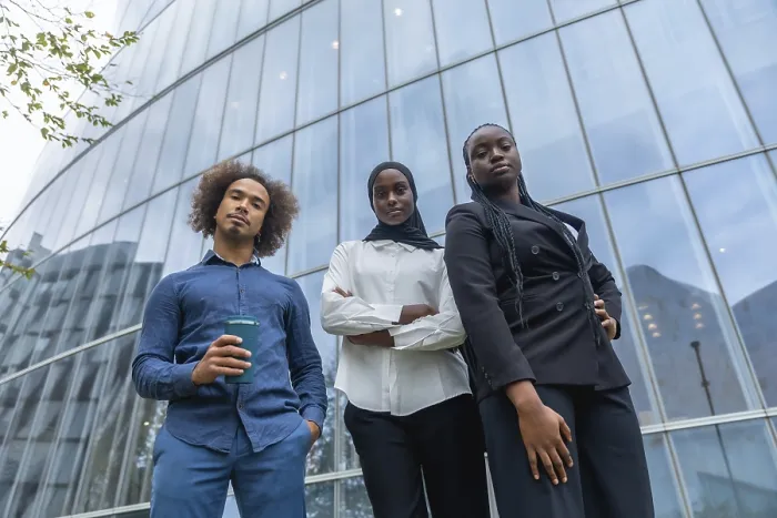 Framed Print : Diverse business team of young professionals standing together with confident expressions against a backdrop of a
