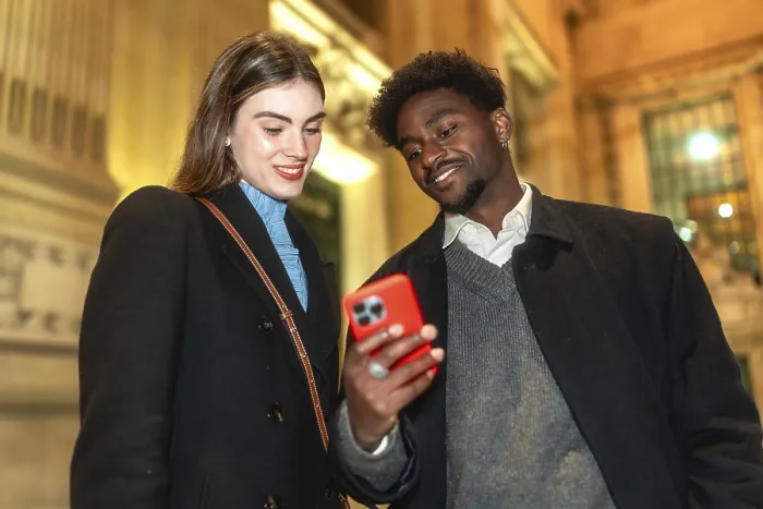 Framed Print : Diverse couple standing close, looking at a smartphone screen and smiling Framed Print : Diverse couple standing close, looking at a smartphone screen and smiling