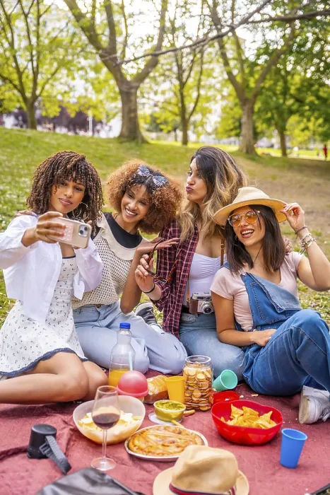 Framed Print : Four diverse female friends are enjoying a picnic in a park