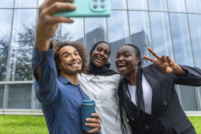 Framed Print : Three diverse friends smiling and laughing while taking a group selfie with a smartphone Framed Print : Three diverse friends smiling and laughing while taking a group selfie with a smartphone
