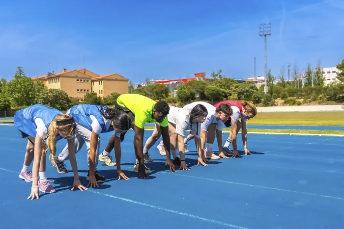 Framed Print : Diverse group of athletes ready to start a race on a blue running track